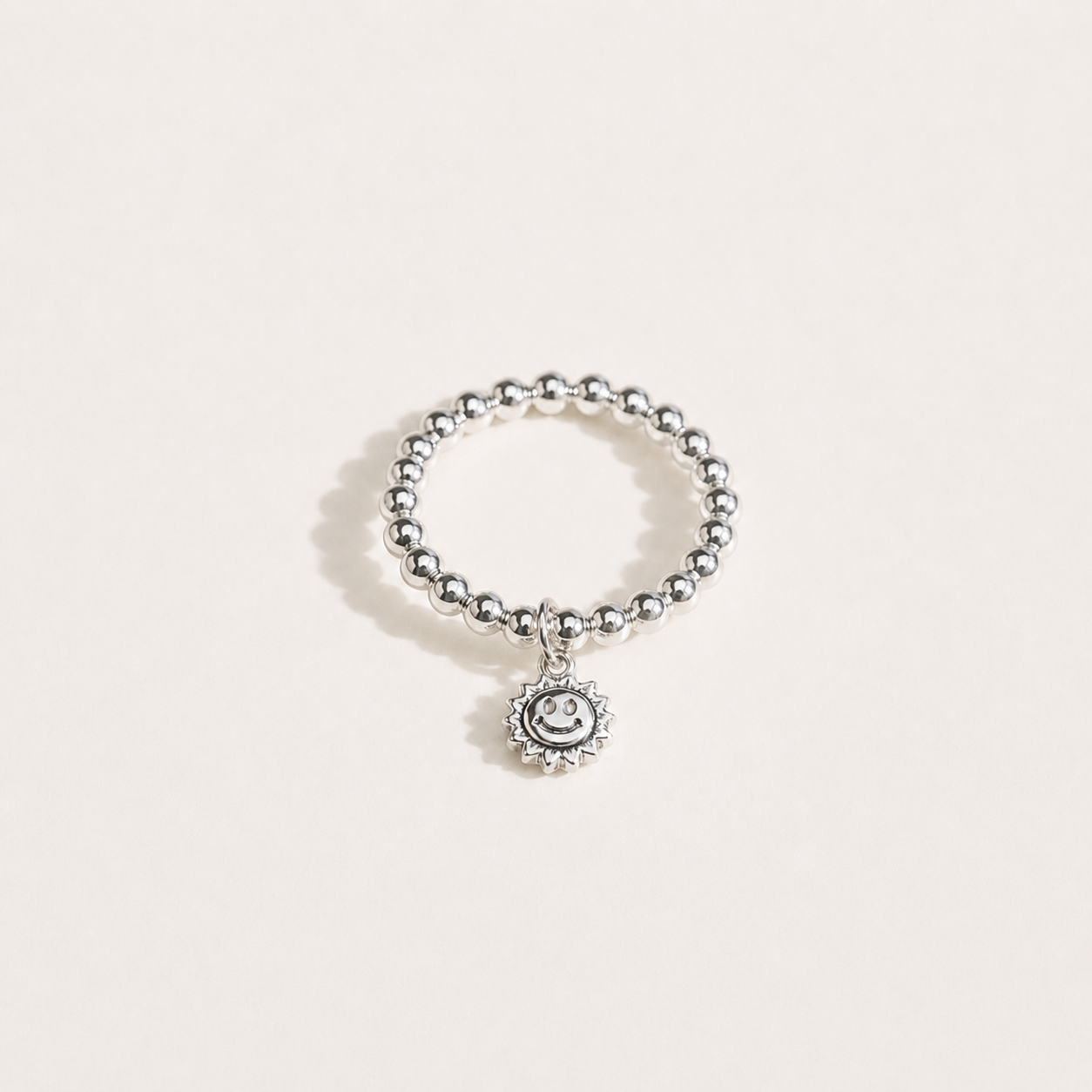 Gemina sterling silver beaded elastic ring with a vintage smiley sun charm